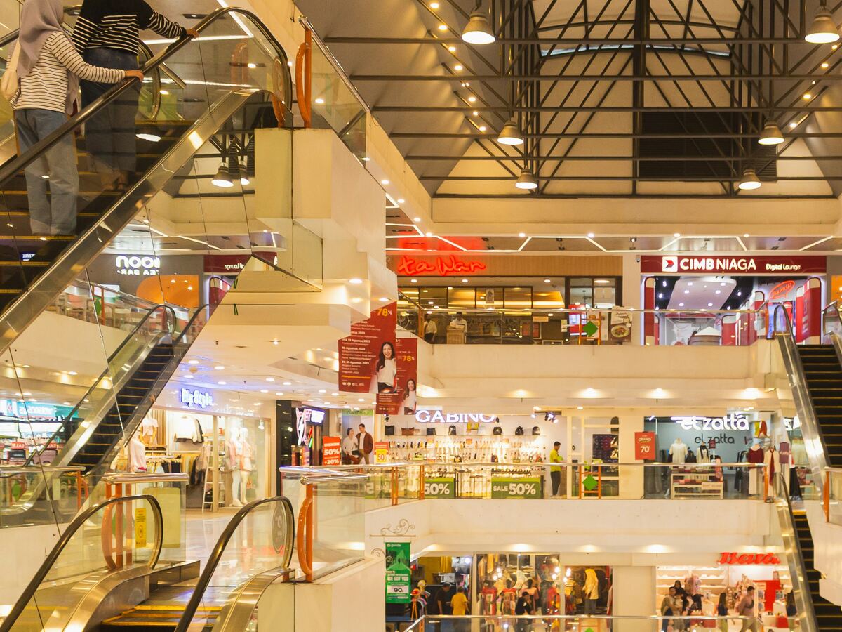 Multi-level shopping mall interior with escalators and storefronts